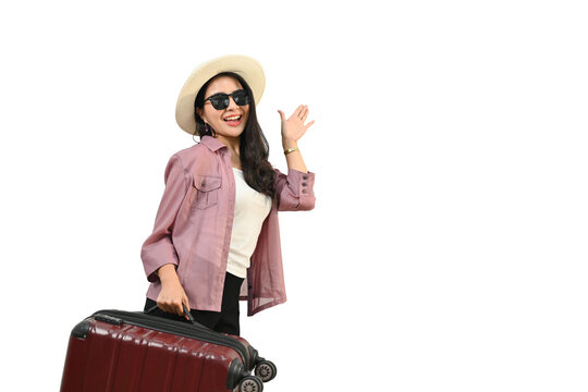 Smiling Asian woman wearing summer hat and sunglasses with luggage standing isolated white background