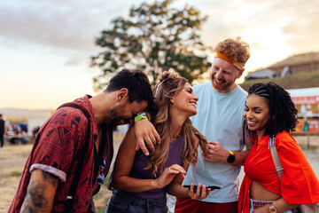 Friends looking up concerts on cellphone at music festival.