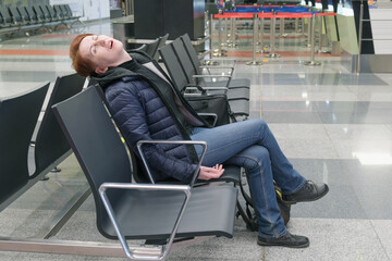 Woman sleeps with her mouth open in the departure area of an international airport. The flight...