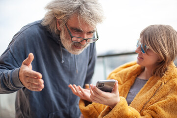 Fototapeta premium Happy family, father and daughter use the phone on the terrace of the solitaire. They laugh and have fun.