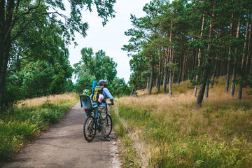 Father and his little child travelling by bike in the forest, the girl is sitting in the child seat