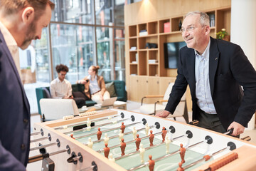 Two business people at the foosball table playing table football