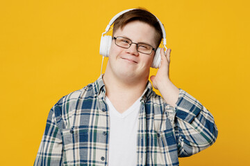 Young smiling satisfied man with down syndrome wear glasses casual clothes headphones listen to...