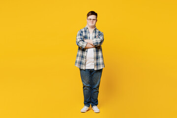 Fototapeta premium Full body young smiling man with down syndrome wears glasses casual clothes look camera hold hands crossed folded isolated on pastel plain yellow color background. Genetic disease world day concept.