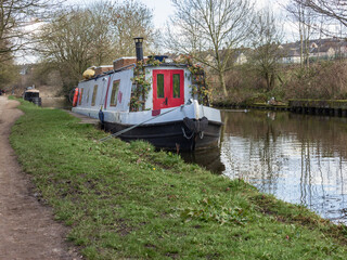 A boat tied up to the towpath of the Leeds and Liverpool Canal at Hirst Wood displays a canal art version of the traditional flowers round the front door