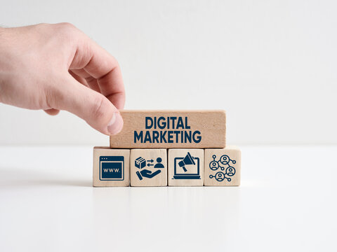 Digital marketing concept. Hand places wooden block with the word digital marketing with business symbols.
