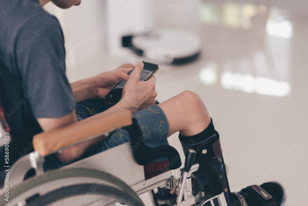 Wall mural Young man using mobile phone for control cleaning robot,Teenage boy using technology do housework instead of humans, Concept Easier lifestyle, Quality of life for people with disabilities.