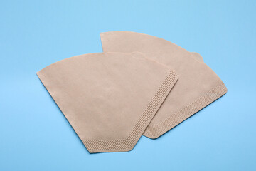 Paper coffee filters on light blue background, flat lay