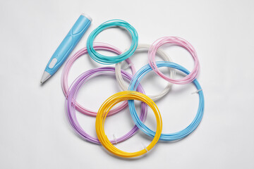 Fototapeta premium Stylish 3D pen and colorful plastic filaments on white background, flat lay