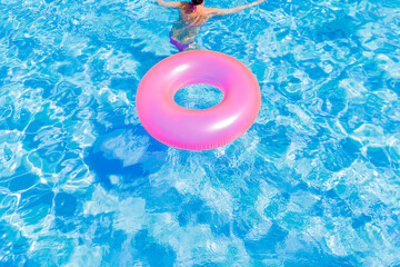 Inflatable life buoys in the pool of teenage girls in bikini and appears swiming inflatable balls.