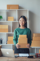 Startup small business entrepreneur or freelance Asian woman using a laptop with box, Young success Asian woman with her hand lift up, online marketing packaging box and delivery, SME concept.