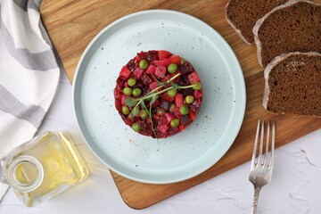 Delicious vinaigrette salad and slices of bread on white textured table, flat lay