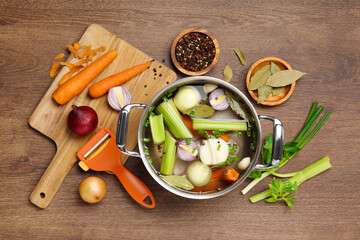 Pot and different ingredients for cooking tasty bouillon on wooden table, flat lay
