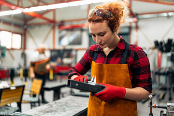 A young woman in STEM measures the dimensions of a metal rod she needs for a project