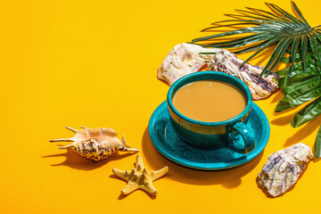 Obraz na płótnie Canvas A cup of coffee in a marine style. Starfish, shells, palm leaves. Hard light, dark shadow