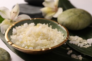 Aromatic sea salt, leaves and flowers on white table, closeup. Spa composition