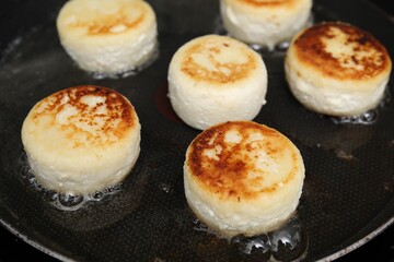 Delicious cottage cheese pancakes in frying pan, closeup