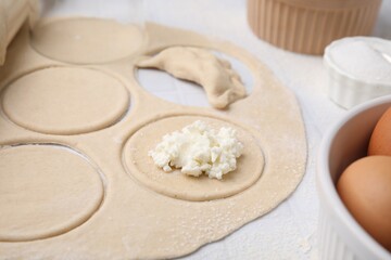 Fototapeta na wymiar Process of making dumplings (varenyky) with cottage cheese. Raw dough and other ingredients on white tiled table, closeup