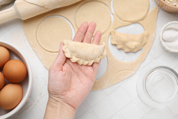 Woman holding dumplings (varenyky) with cottage cheese at white table, closeup