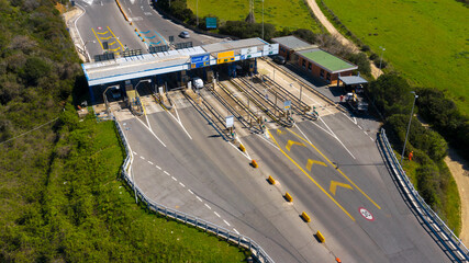 Aerial view of an Italian highway toll booth. There are lanes for paying the toll by debit card,...