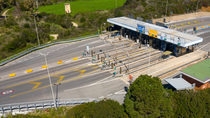 Aerial view of an Italian highway toll booth. There are lanes for paying the toll by debit card,...