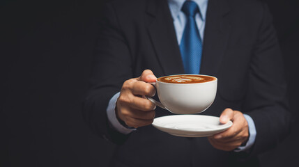 Businessman in a suit is holding a cup of coffee while standing on a black background