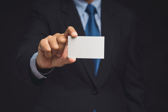 Businessman showing a blank white name card mockup while standing on a black background