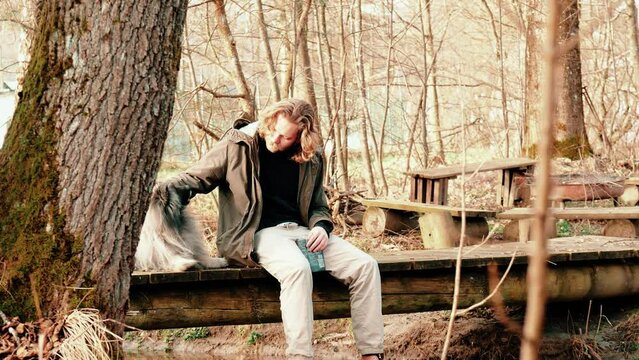 it is a warm, sunny autumn day. A blond young man and his grey Wolfspitz spend the afternoon in the forest and have made themselves comfortable on a bridge before continuing their walk.