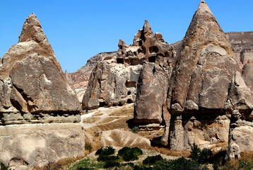 Landscape with mushroom-shaped mountains (also called Fairy Chimneys) against a bright blue clear sky in the Rose Valley between the towns of Goreme and Cavusin in Cappadocia, Turkey