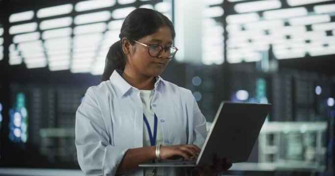 Portrait of a Technological Software Engineering Department Manager Standing and Using a Laptop Computer. Indian Female Focused on Thinking while Working in the Office