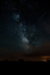 the milky way in the countryside with nebulae and a meteor trace on the image