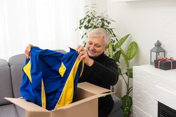 Elderly woman unpacking things in new house. Female hands opening cardboard box. Real estate, purchase, moving concept.
