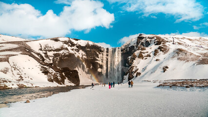 arco-íris em Skógafoss na Islândia com neve no inverno e com pessoas