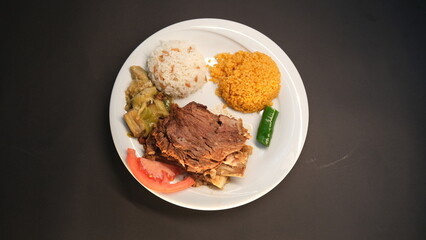 Beef breast ribs served with rice and appetizers on a serving plate