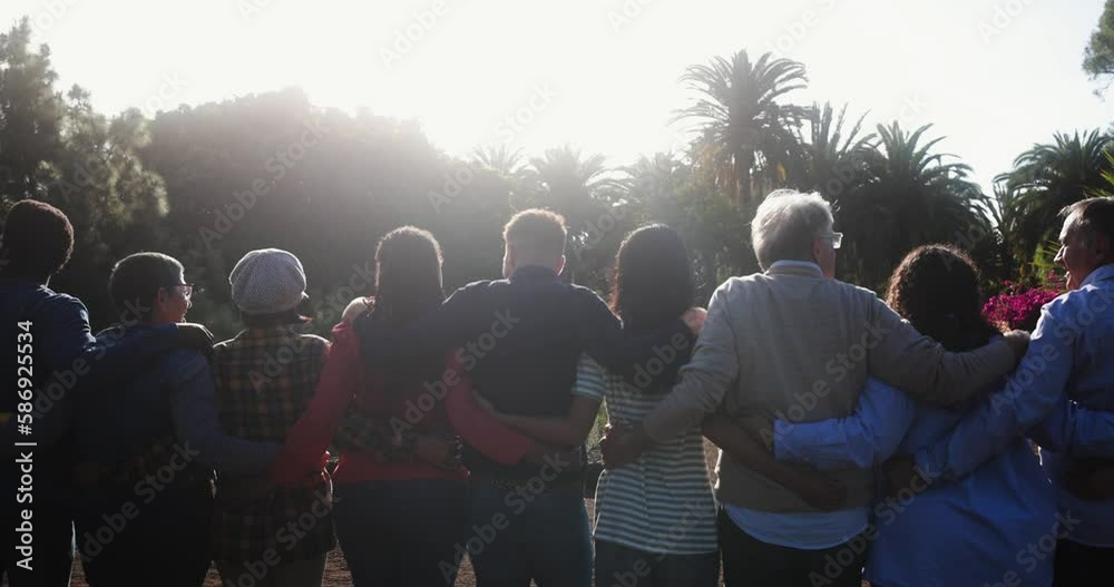 Wall mural Crowd of multigenerational people hugging each other in front of camera - Multiracial friends with different ages having fun together at city park 