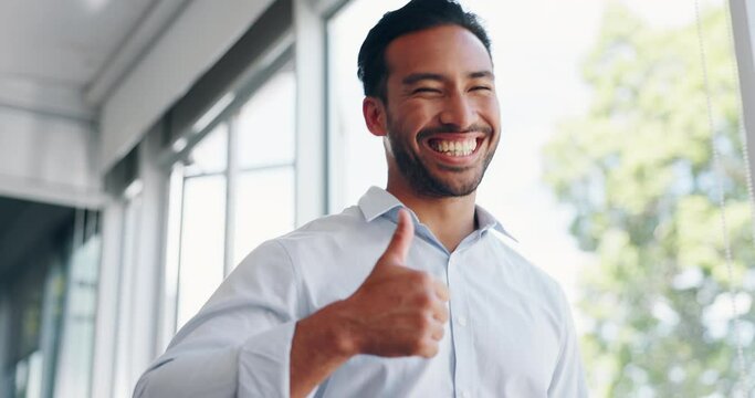 Businessman, thumbs up and wink while walking in office for success, motivation or thank you. Face portrait, yes and male employee from Singapore with hand gesture for support, like emoji or approval