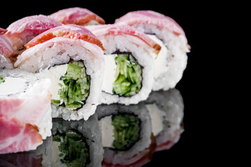 sushi roll with cream cheese cucumber bacon on a black mirror background
