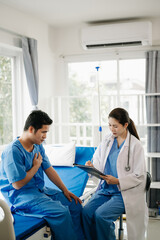 Obraz premium Asian male patient on bed while doctor hands of checking examining his pulse for record the treatment results in hospital.