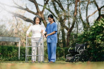 Asian careful caregiver or nurse and the happy patient in a wheelchair are walking in the garden to help and encourage and rest your mind with green nature. 