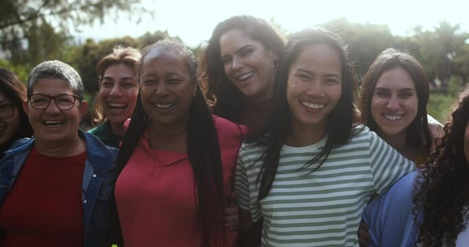 Group of multigenerational women hugging each other outdoor - Multiracial female friends with different ages having fun together at city park 