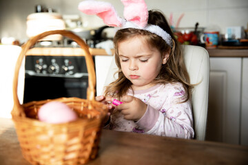 Little beautiful girl with easter bunny ears on with her basket of easter eggs.Happy Easter holiday.