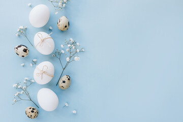 Composition with Easter eggs and flower blossom on blue background. Minimal easter concept.