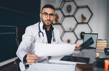 Positive doctor with document and x ray image in clinic