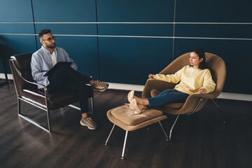 Young male therapist sitting with female client in modern room