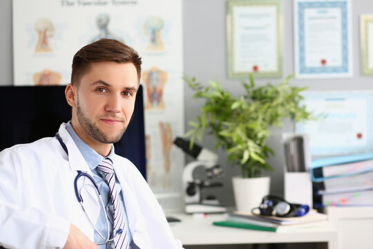 Portrait of young doctor sits in clinic office. Medical services insurance and examination in hospital
