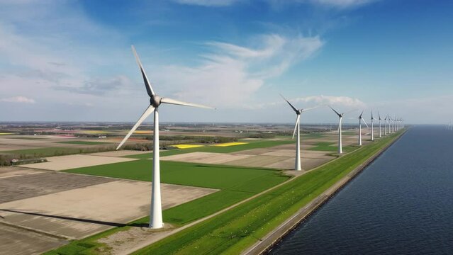 Wind turbines on a levee producing sustainable renewable energy in a wind park. Drone point of view.