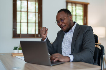 Fototapeta premium middle aged man American African business man holding computer laptop with hands up in winner is gesture, Happy to be successful celebrating achievement success