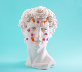 David head statue with pills and tablet oh his face. Concept of drug and dietary supplements addiction.