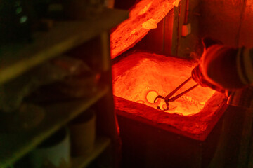 potter takes out the pottery with tongs from a red-hot electric muffle furnace for firing
