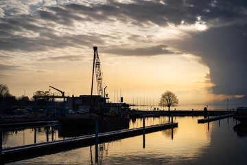 Fototapeta na wymiar Port au coucher du soleil avec une grue sur un barge de travail